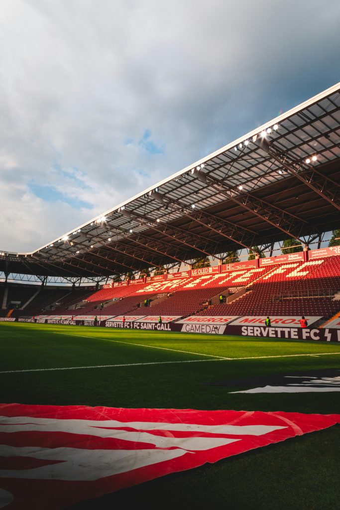 A view of Stade de Genève with empty grandstands during dusk, perfect for sports events and tournaments.